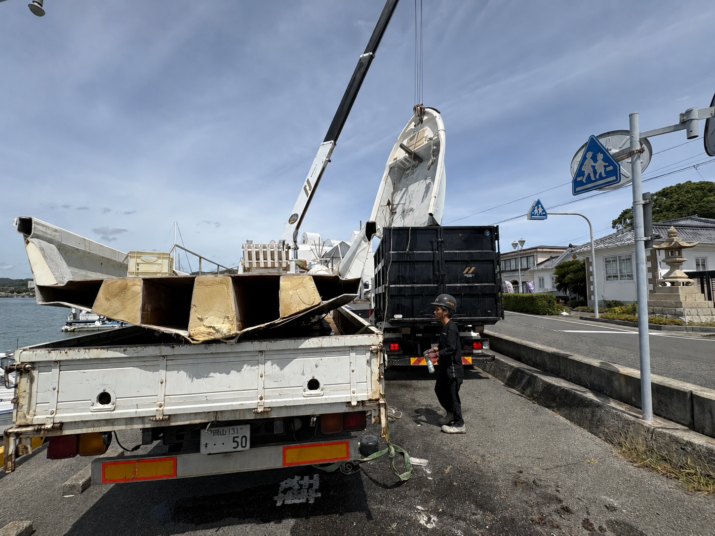 切断した船体をトラックの荷台へ積み込んでいる様子