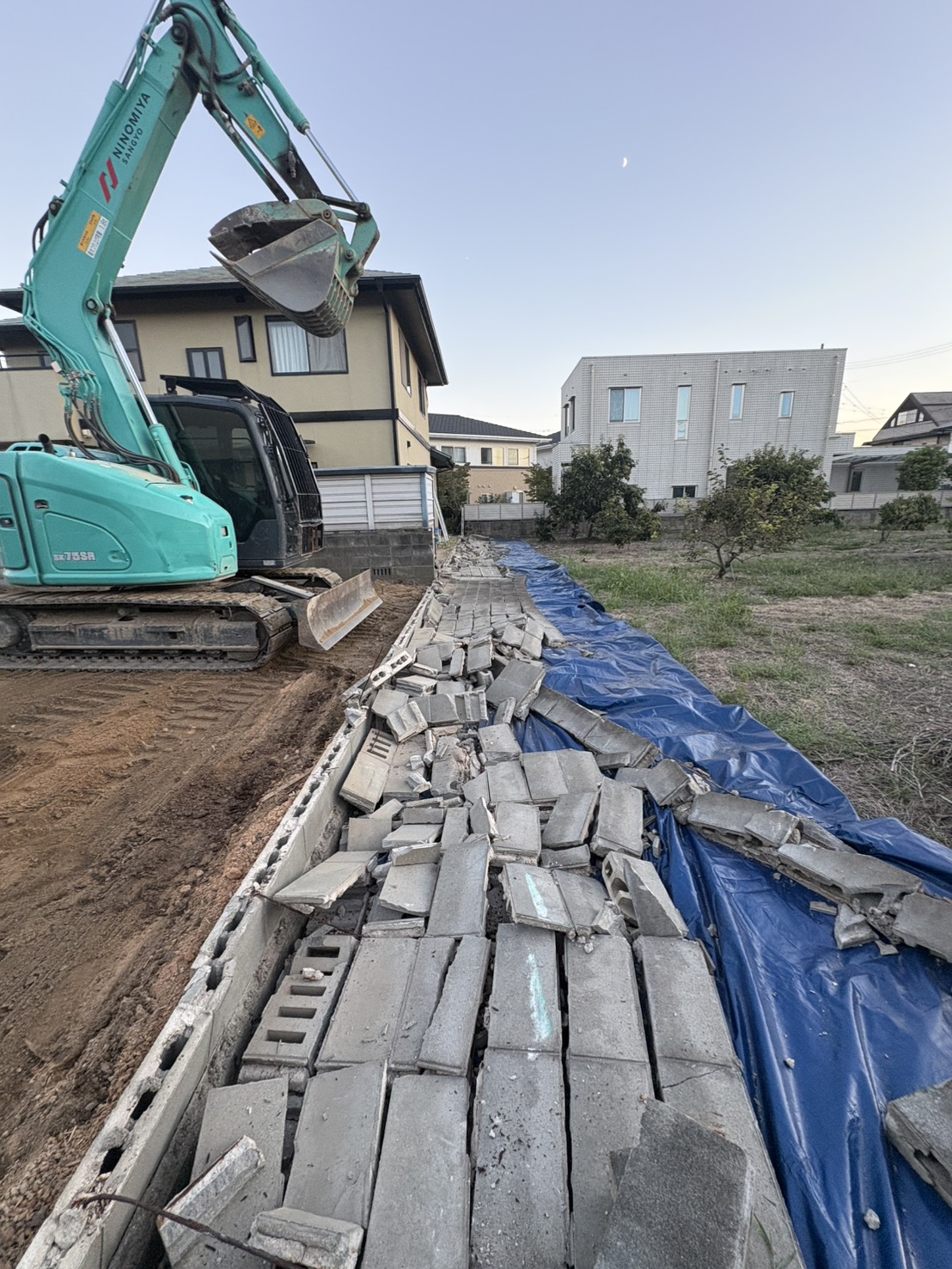 解体した道路側ブロック塀をブルーシート上にまとめている様子